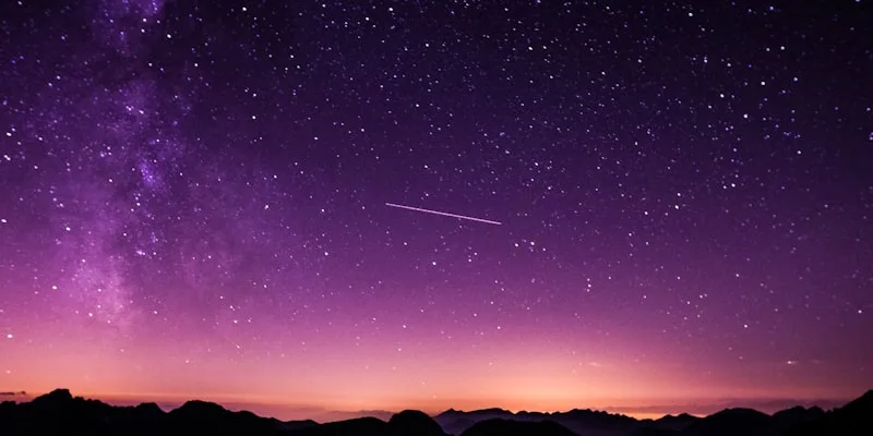 The Milky Way arching over a dark mountain summit, an image of the career north star